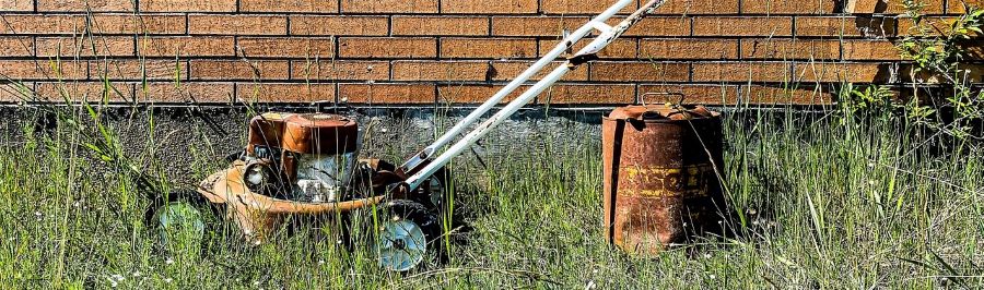 A used lawn moer in the grass.